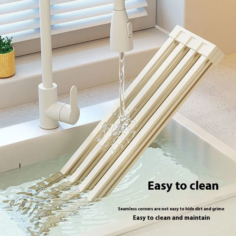 Foldable milky white stainless steel kitchen draining rack with dishes, shown next to a sink.