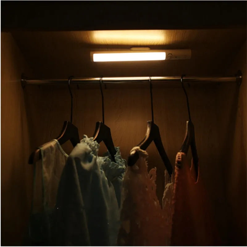 Slim white human body induction LED cabinet light with magnetic base for sticking to metal surfaces.