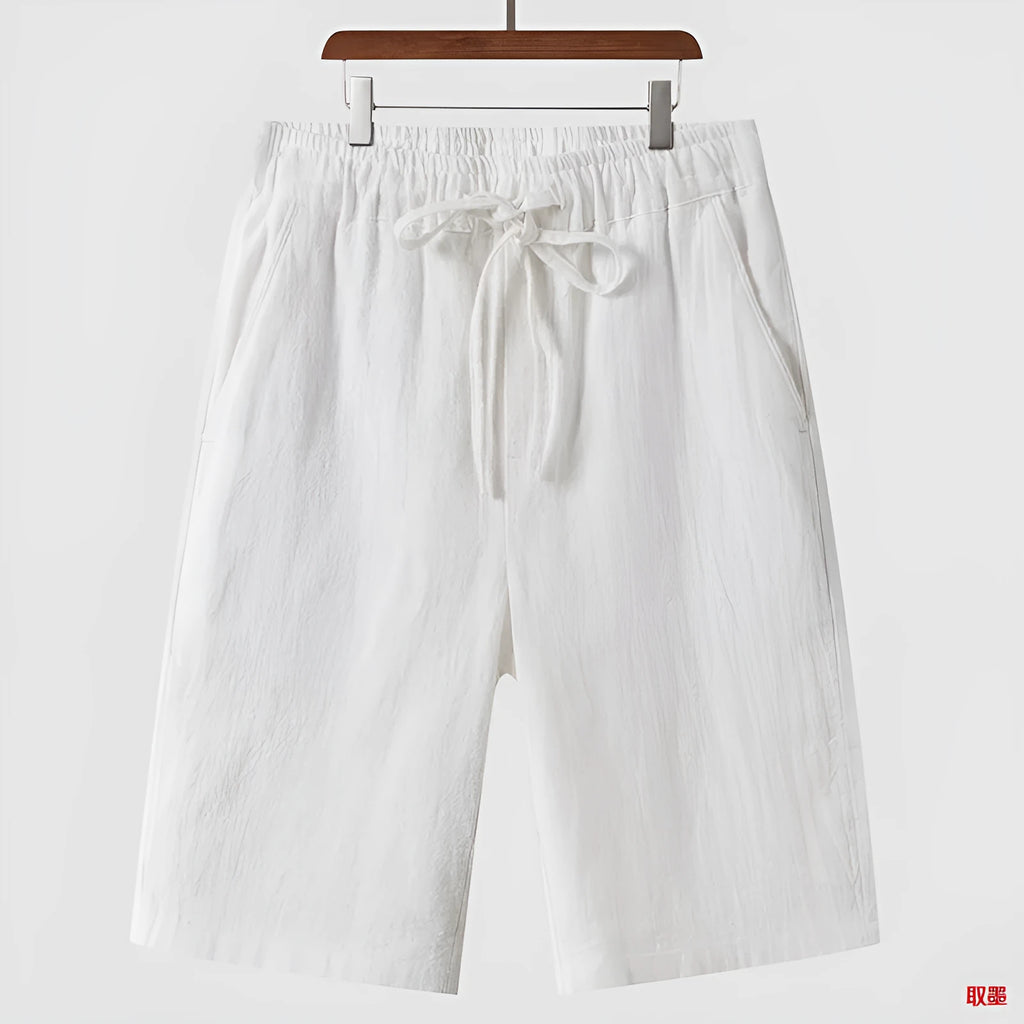 Man wearing beige linen cropped shorts with a loose fit and elasticated waistband.