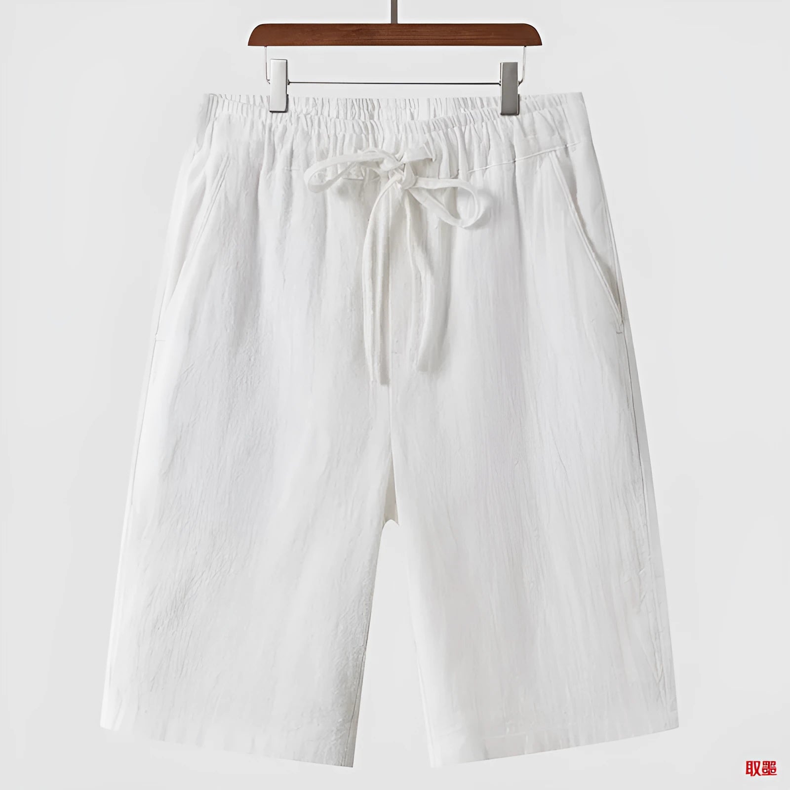 Man wearing beige linen cropped shorts with a loose fit and elasticated waistband.