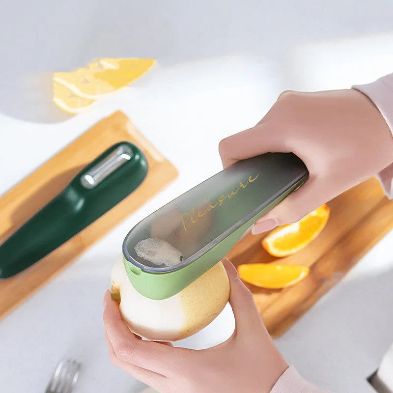 Dark green vegetable peeler with stainless steel blade inside its clear plastic storage tube on a kitchen counter.