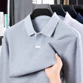 Men's grey cotton polo shirt with lapel collar and asymmetric design, shown in a loose fit.