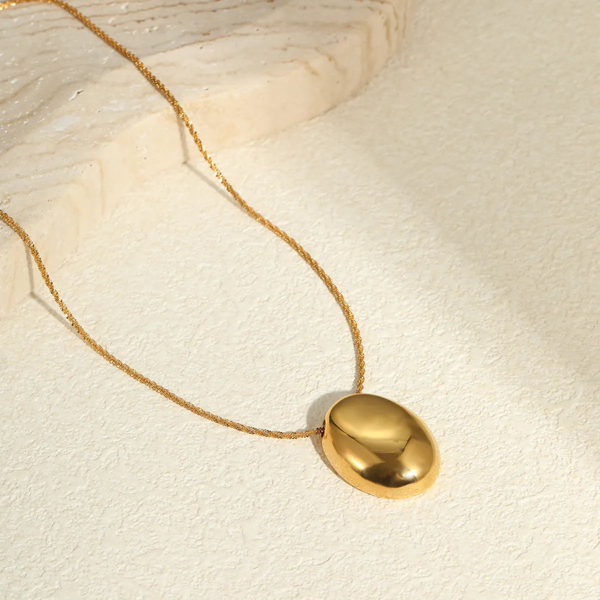 Gold-plated geometric necklace with stainless steel chain on display showing pendant detail