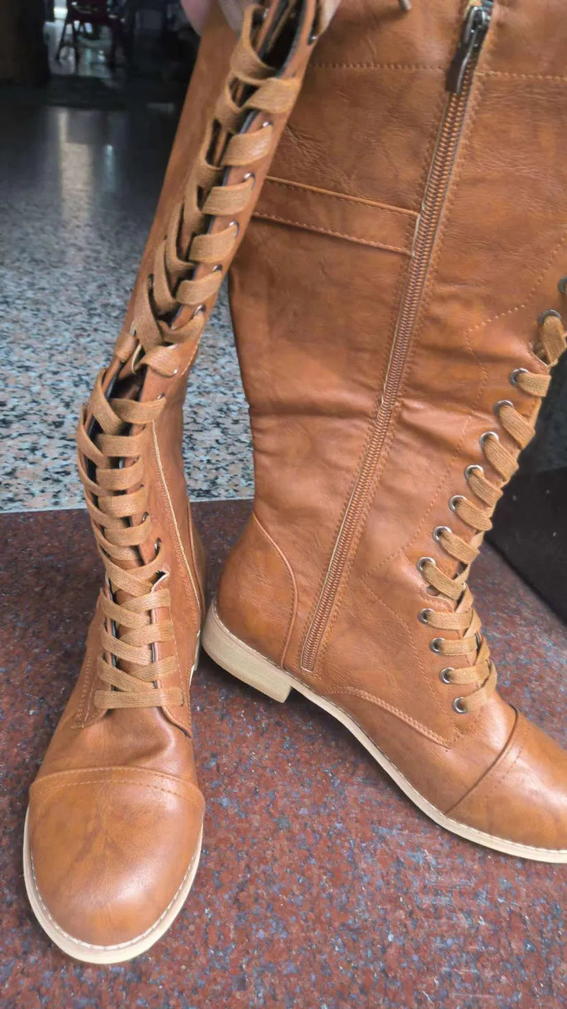 Women's black knight boots with cross-strap design across ankle in synthetic PU material