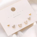 Three pairs of heart-shaped alloy earrings in gold, black, black and white, and pink colours with electroplated finish