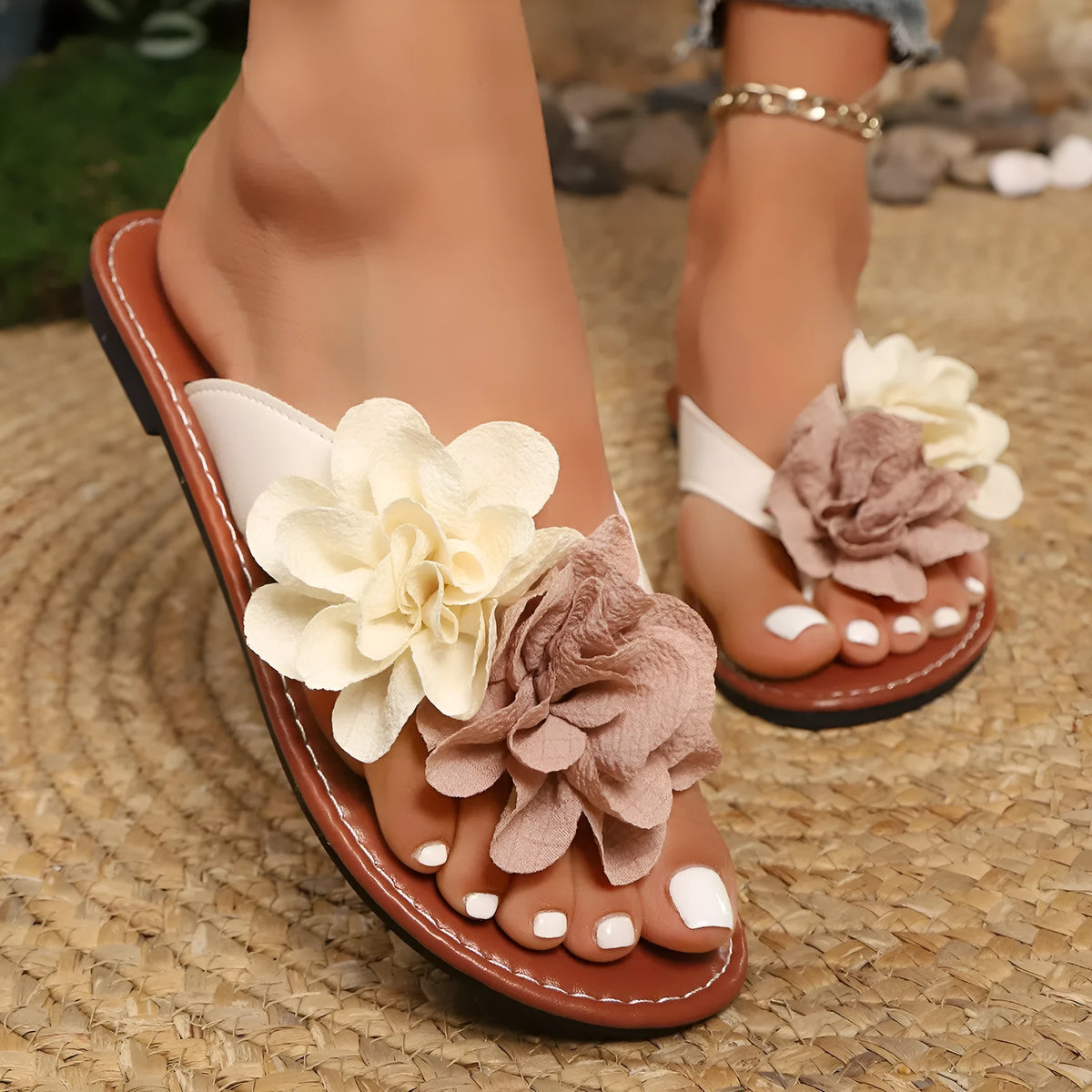 Beige flip flop open toe flat sandals with adjustable strap and two-way flower decoration on a beach setting