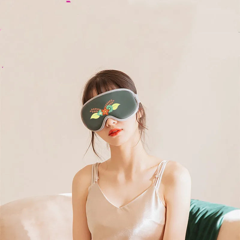Green portable USB eye spa mask showing suede shell and super fibre interior on a desk.