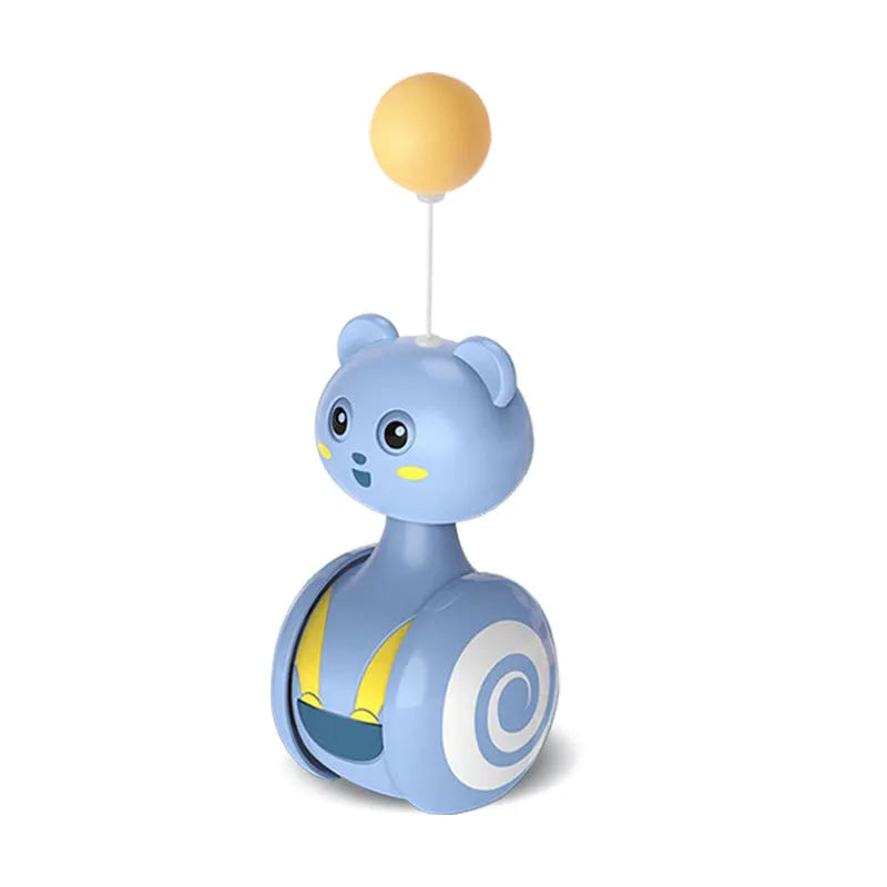 Pink and blue cat tumbler toys with feather lures and rolling balls on a wooden floor.