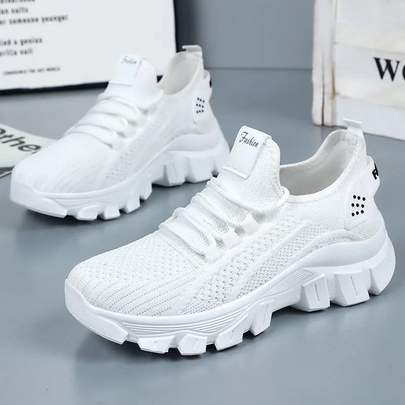 Women's white Flyknit lace-up sneakers with a thick PVC sole and round toe on a neutral background.