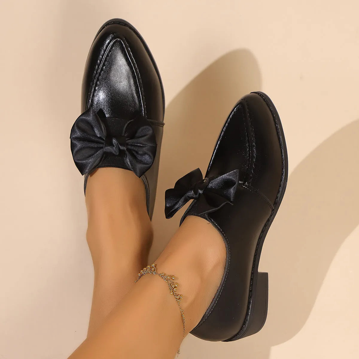 Women's British-style leather-look slip-on shoes with a decorative bow on the front