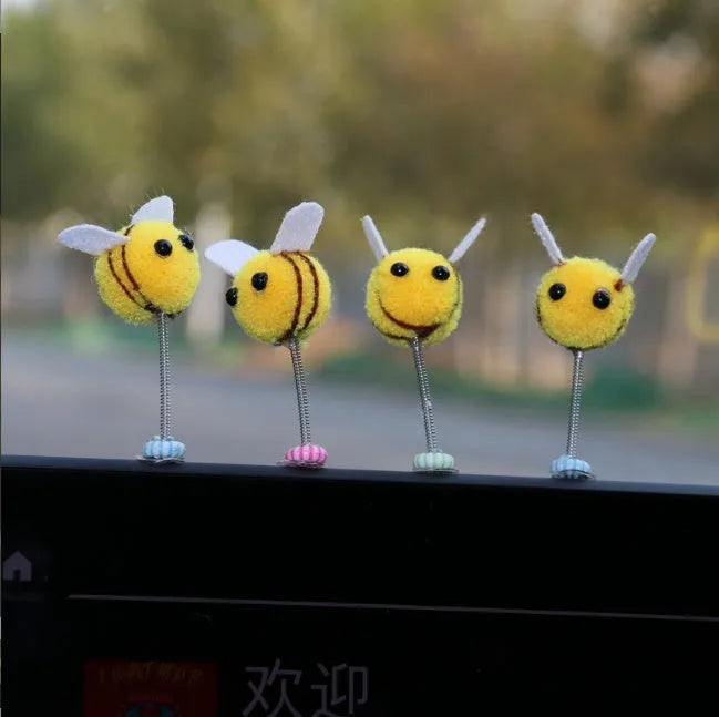 Small, soft, cartoon bee car decoration made from yellow and black fur ball material.