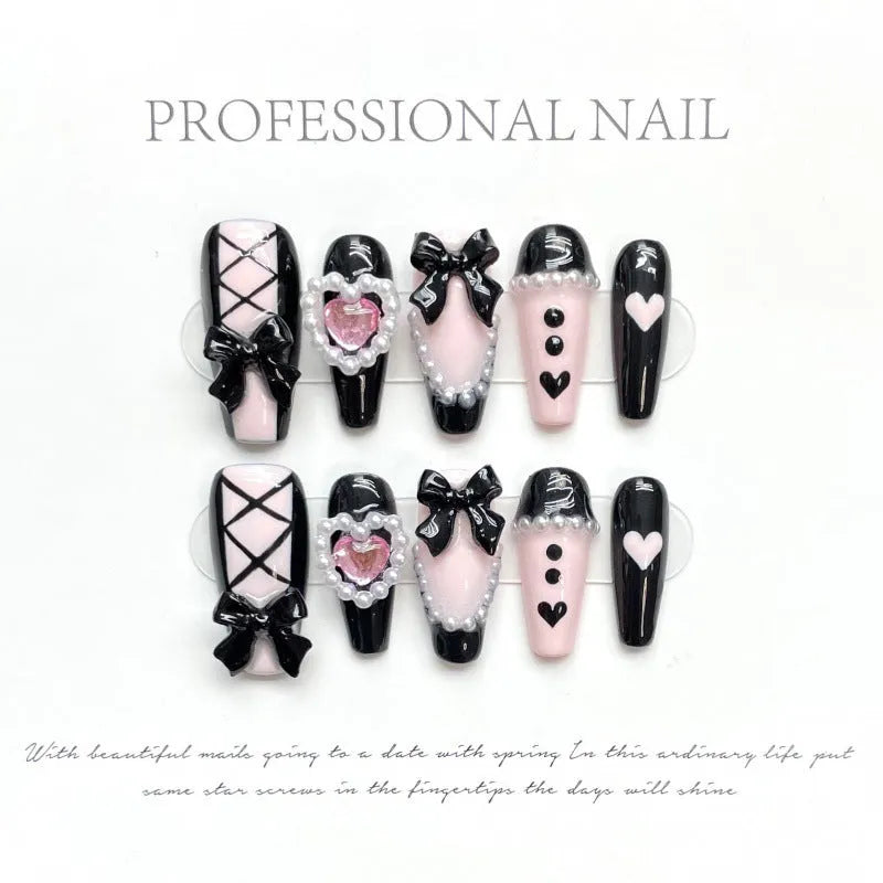 Handmade black and pink heart design artificial nails with bow, Xingx pattern, and cat's eye finish.