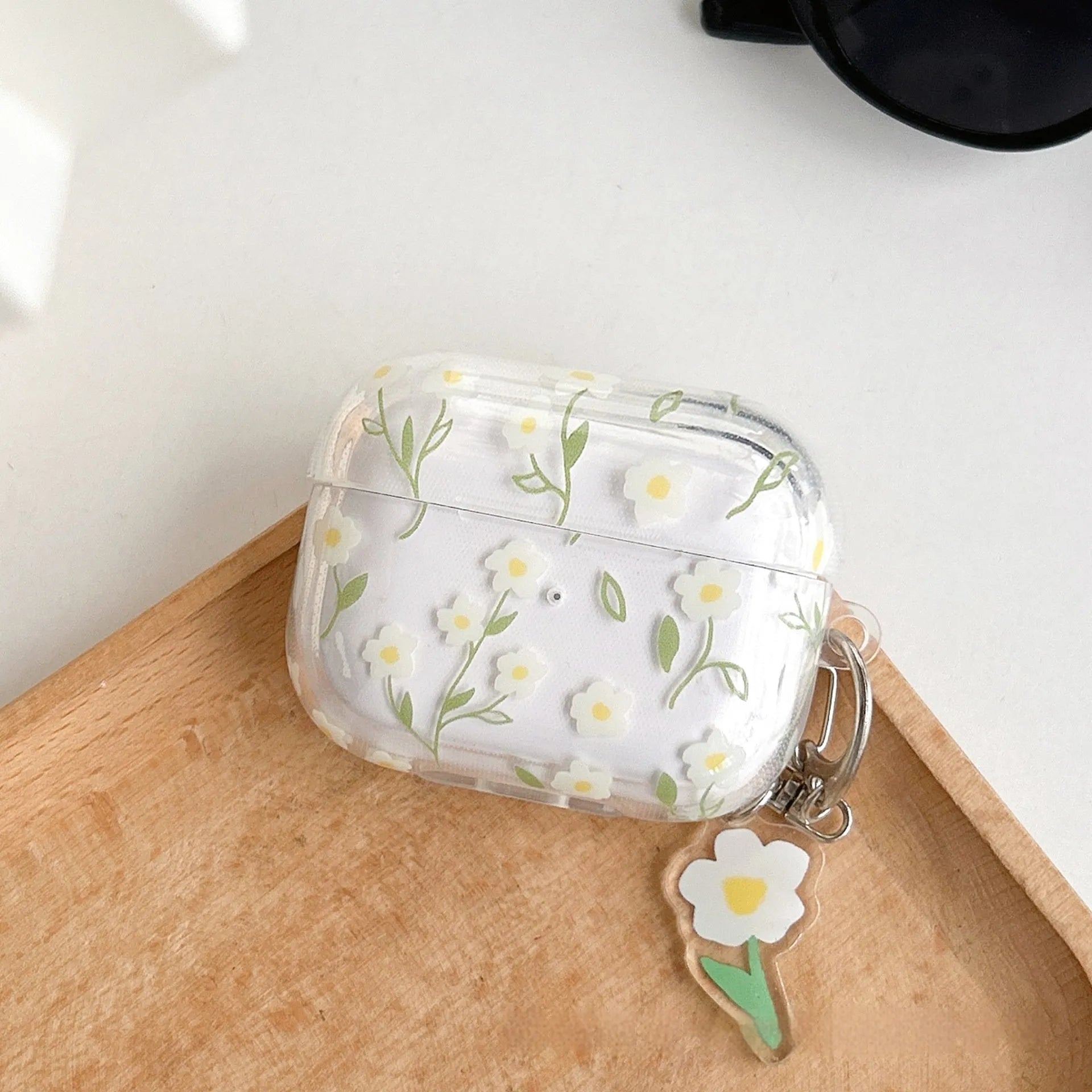 Transparent white floral TPU protective case for Apple AirPods headphones on a table.