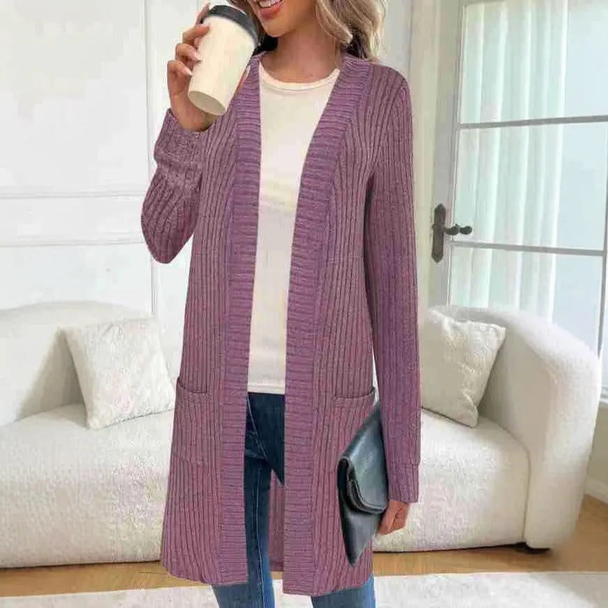 Woman wearing a loose grey long sleeve knitted cardigan jacket with pockets.