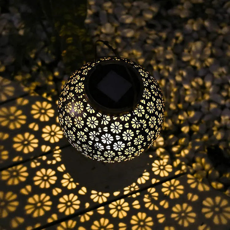 Solar wrought iron hollow flower projection lamp with warm white LED light and shadow pattern on grass