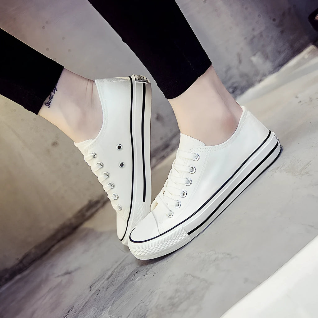 Women's casual canvas shoes in solid colours on a flat sole, showing lace-up fastening.