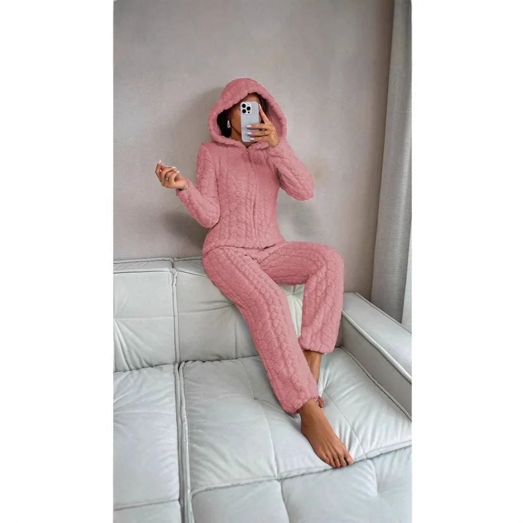 Beige hooded thickened coral fleece one-piece pajama with long sleeves on a woman standing indoors