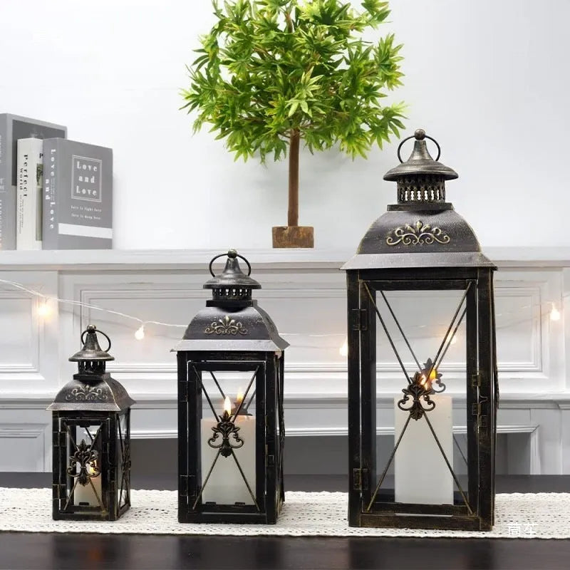 Black and white wrought iron floor-standing storm lantern with tempered glass panels in three sizes for courtyards.