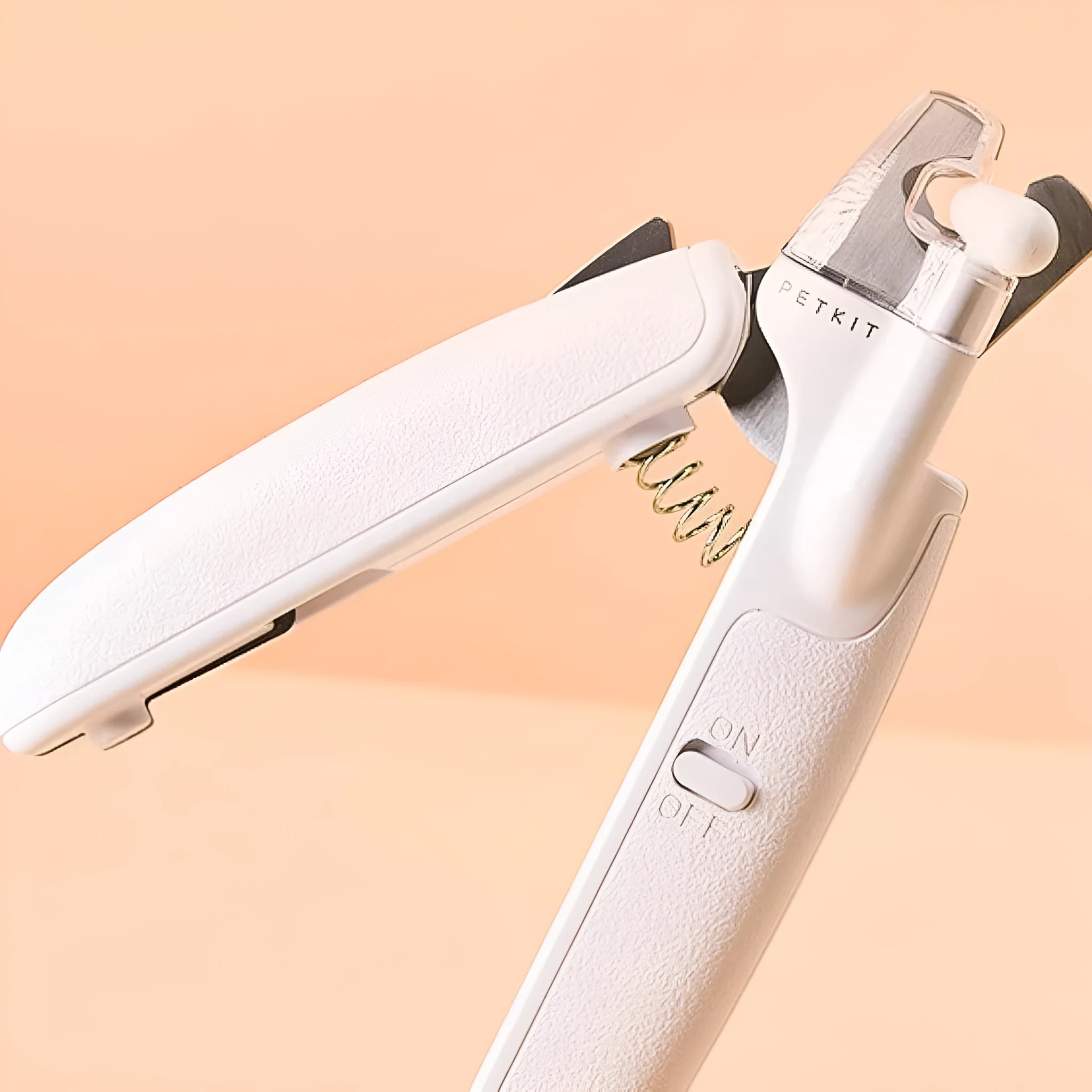 White pet nail clippers with LED light, transparent guard, and a nail file on a table