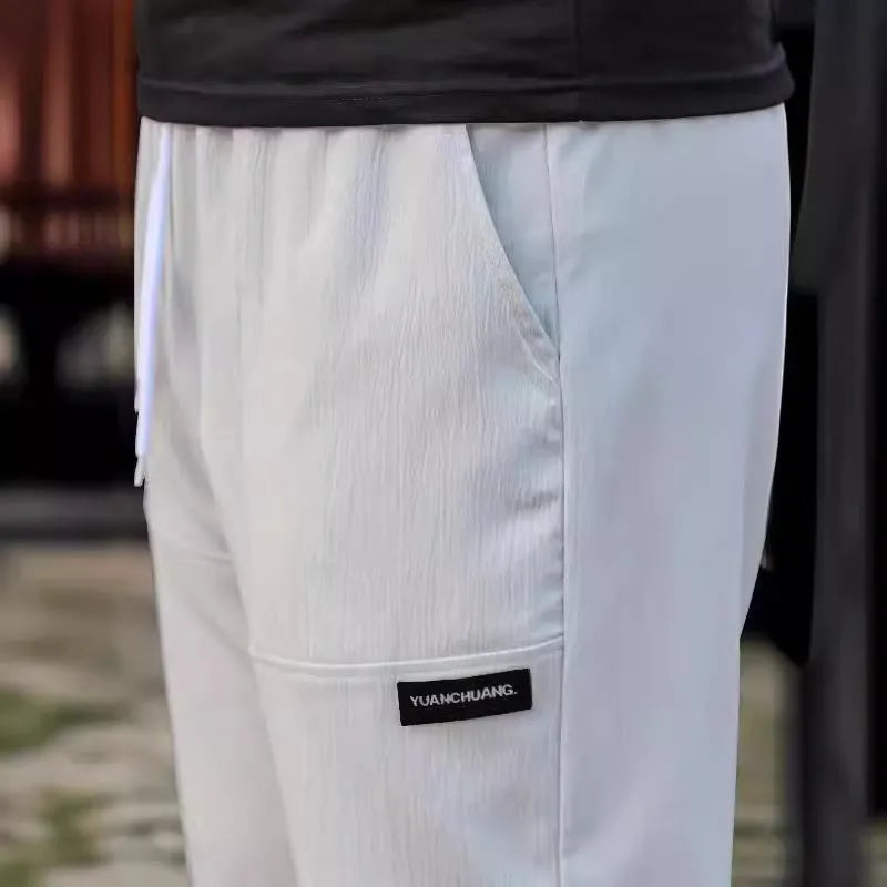 Men's light grey polyester casual trousers laid flat showing front design.