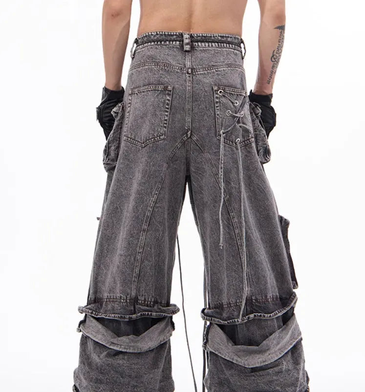 A pair of grey distressed denim overalls with rope stitching, shown on a model.
