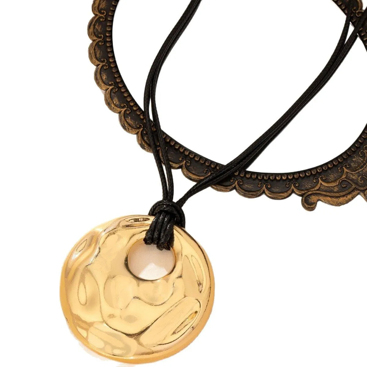 Women's gold alloy oval pendant necklace with braided rope chain on a plain background