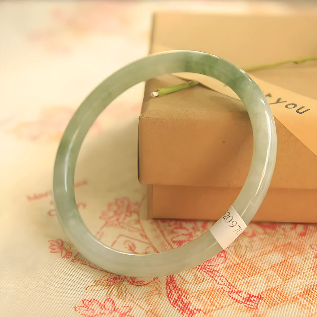 Green jade waxy stone geometric bracelet with Chinese style design on a wrist.