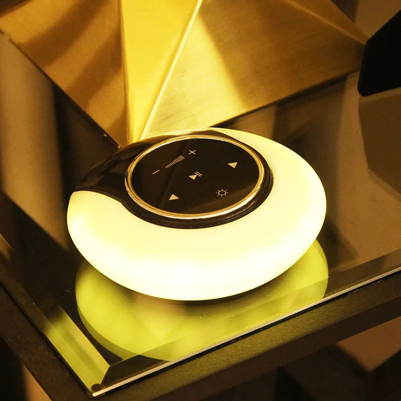 A blue and white foldable Bluetooth desk lamp with integrated speaker and touch controls on a wooden desk.
