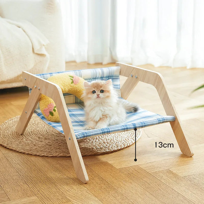 Wooden A-frame cat hammock bed with blue cloth, elevated off the floor on a carpet.