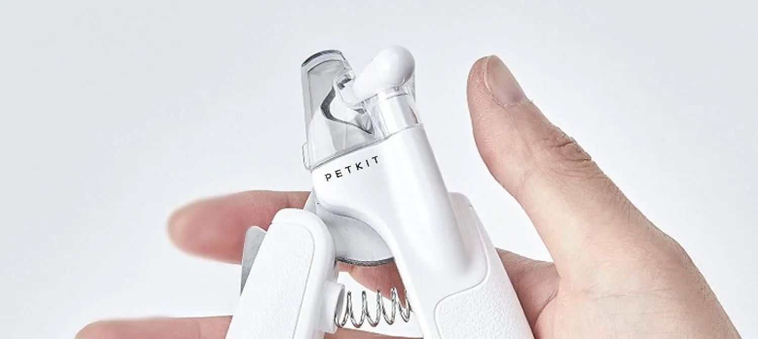 White pet nail clippers with LED light, transparent guard, and a nail file on a table