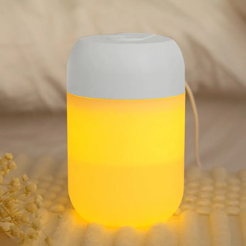 White cylindrical mini USB aromatherapy humidifier on a desk with charging cable.