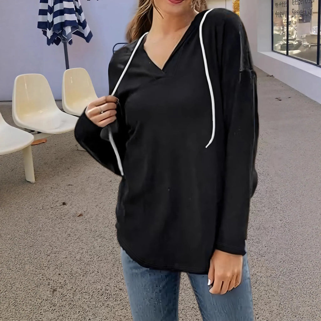 A woman wearing a red V-neck hooded sweatshirt with long sleeves, shown in a loose fit.