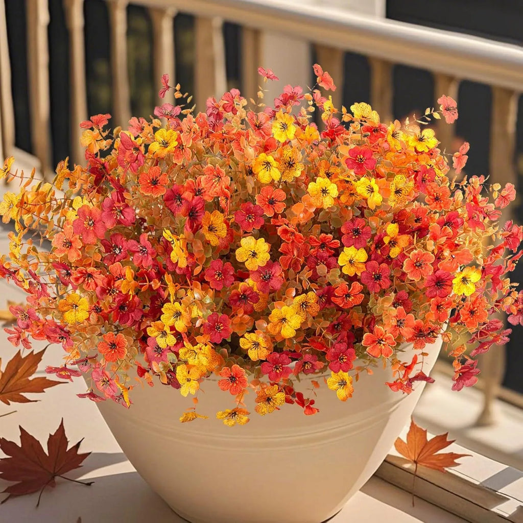 Plastic and silk artificial flower bouquet in autumn colours of red, yellow, orange and orange-yellow.