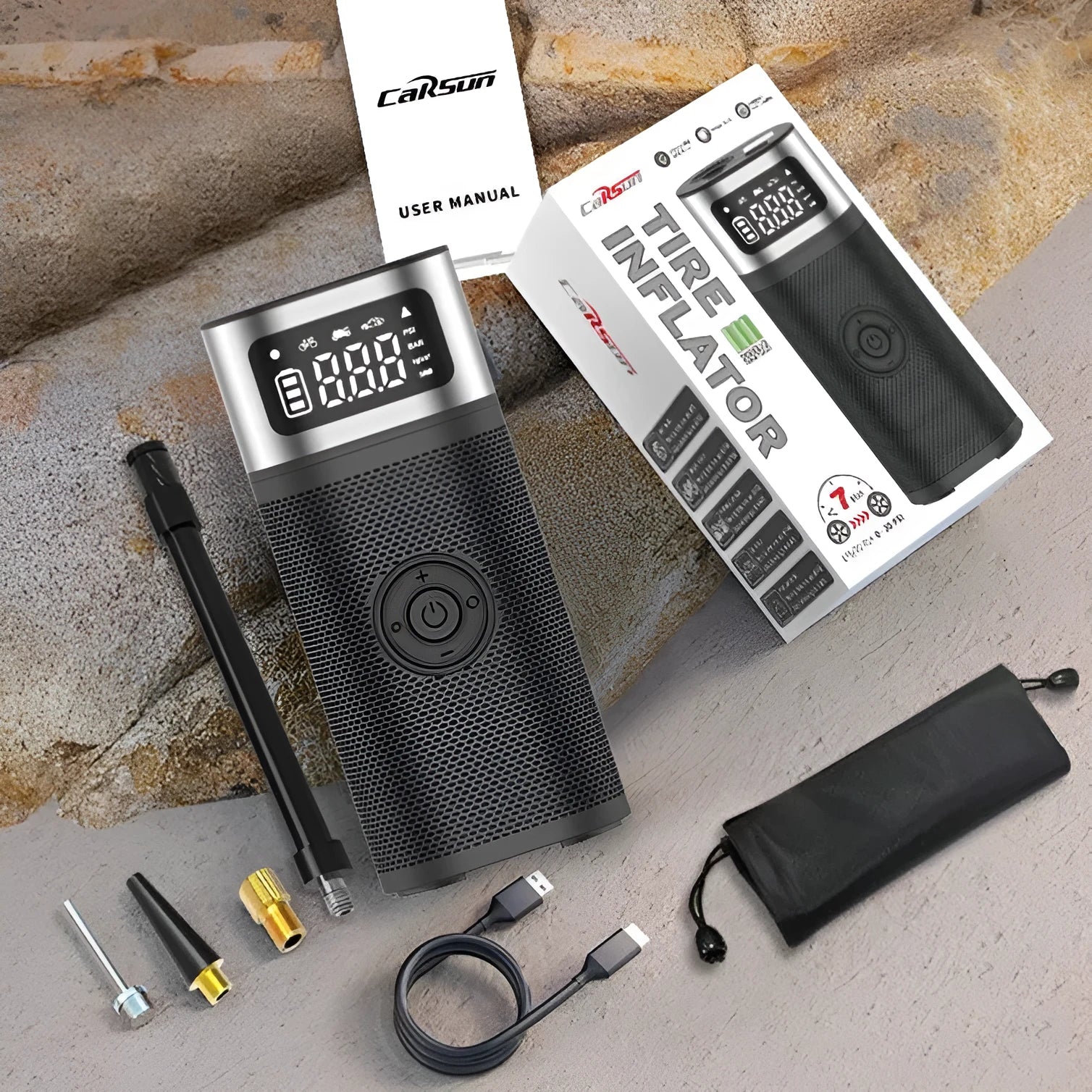 Black portable wireless smart vehicle air pump with hoses and nozzles on a storage bag.