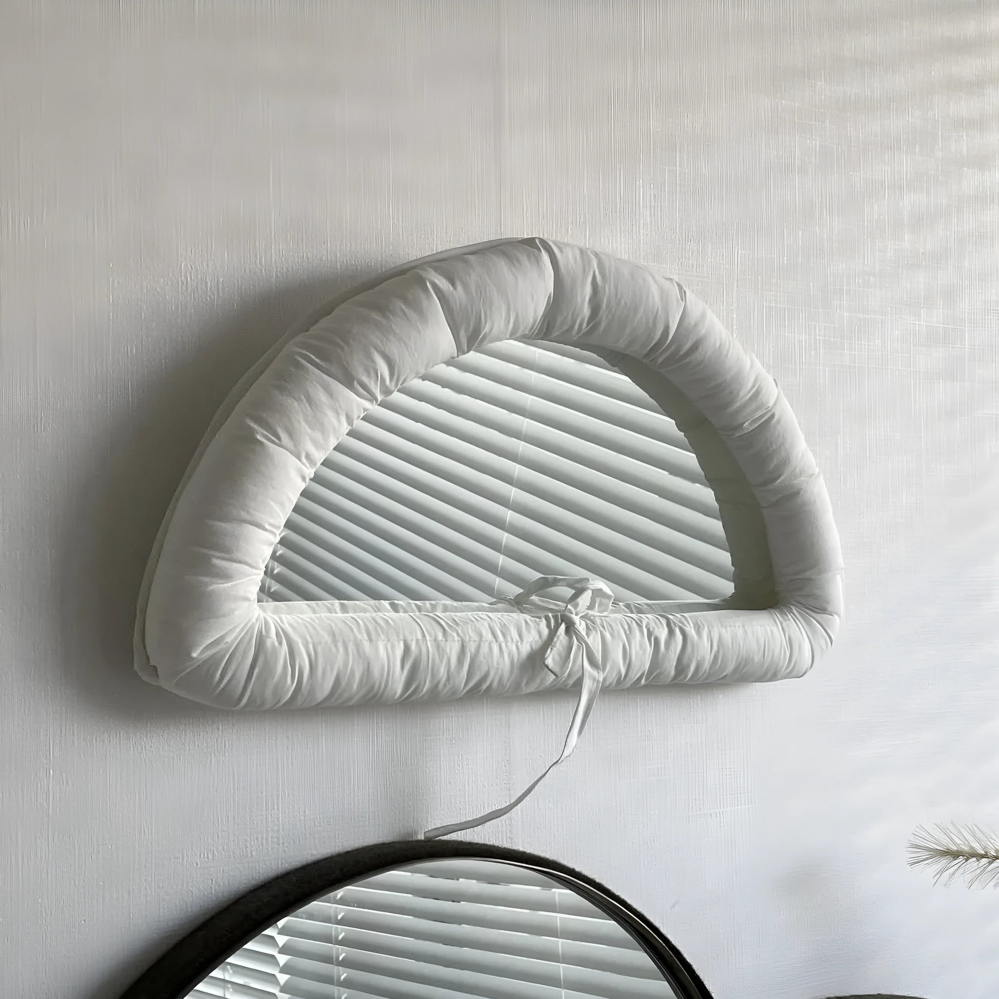 Hanging soft cotton-filled fabric mirror in solid colour on wall