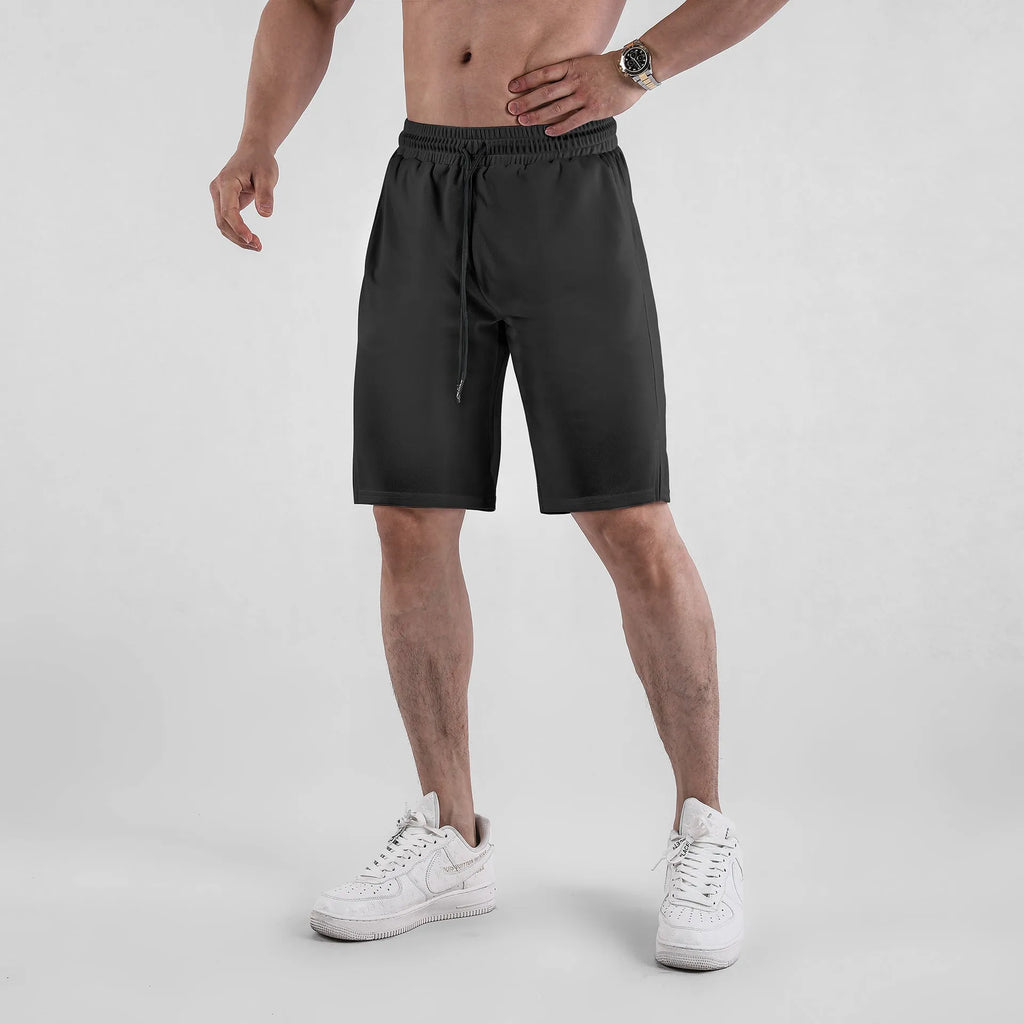 Man wearing loose black capri-length fitness shorts with an elasticated waistband.