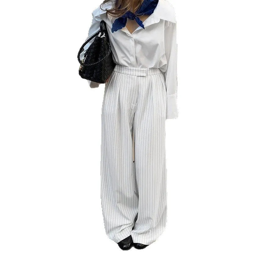White striped wide-leg women's trousers with a loose fit and zipper fastening on a hanger.