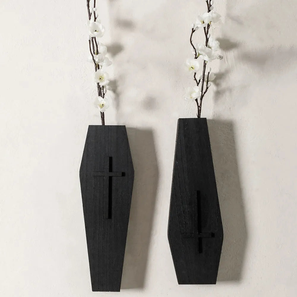 Black wooden cross-shaped wall shelf with space for holding small plants or decorative items.