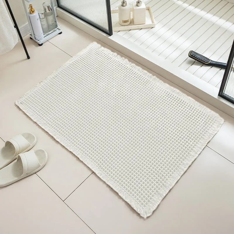 Checkered patterned non-slip absorbent bathroom floor mat in a neutral colour on tiles.