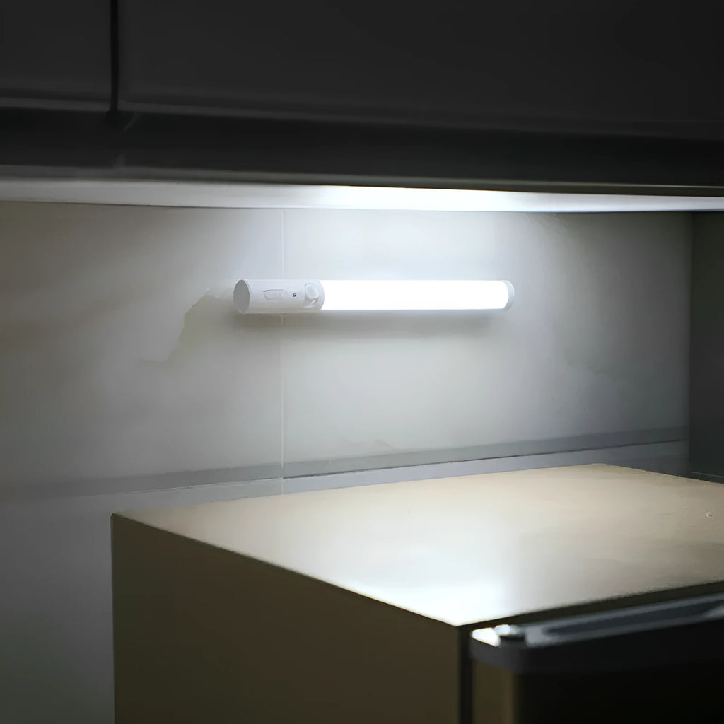 Slim white human body induction LED cabinet light with magnetic base for sticking to metal surfaces.