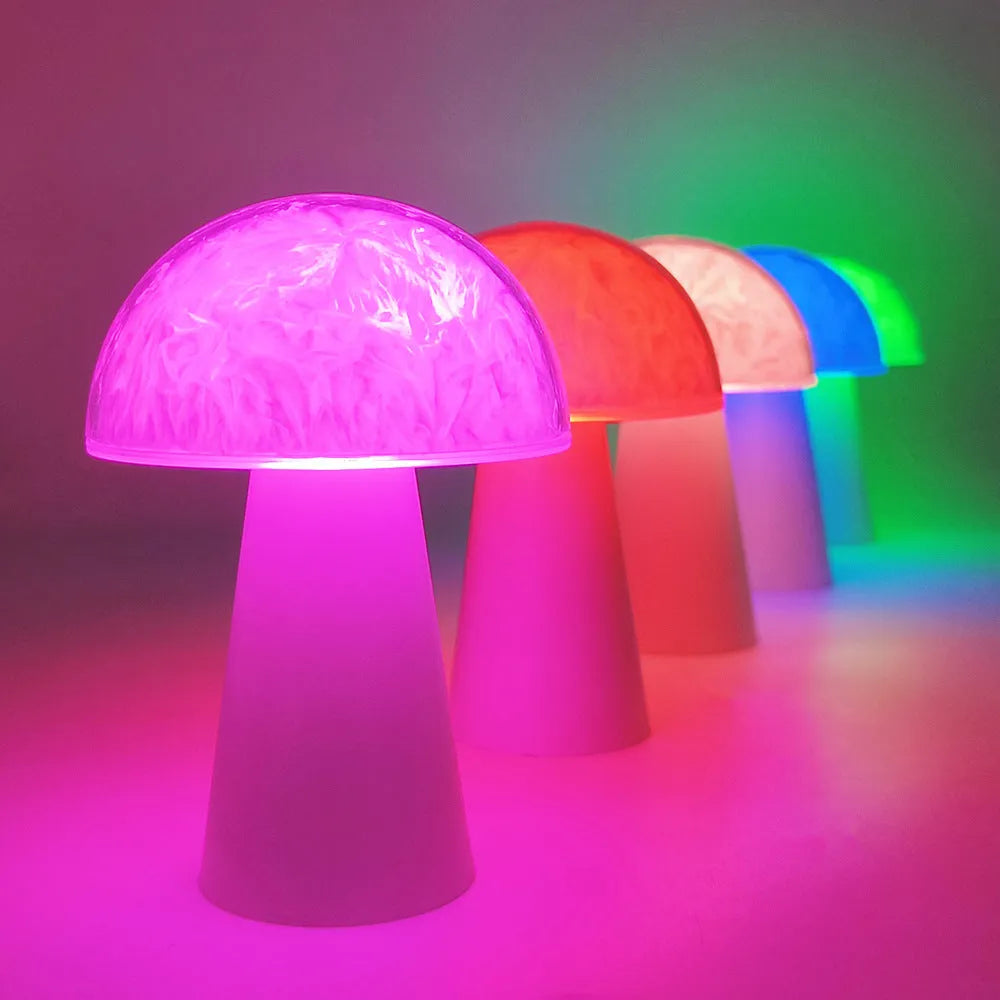 Small white mushroom-shaped night light with colourful RGB glow on a wooden table.