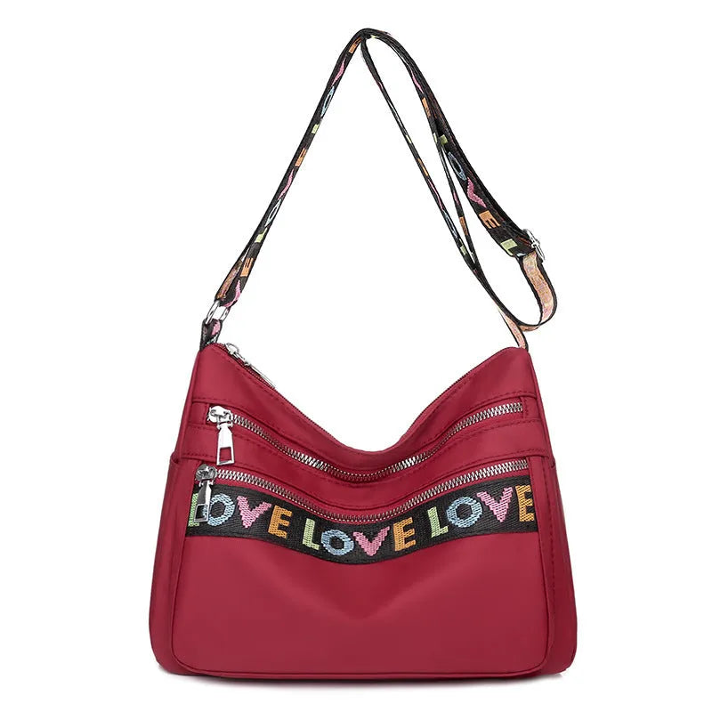 Oxford cloth crossbody shoulder bag in red or black with single strap, multi-pocket large capacity, and letter stitching details