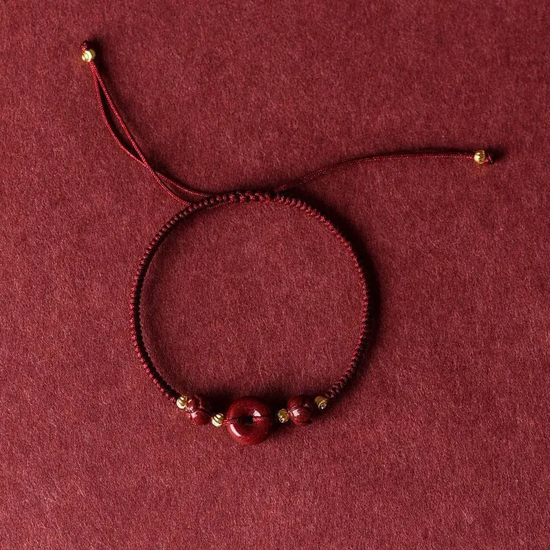 Heart-shaped cinnabar pendant on adjustable safety buckle bracelet with red cord