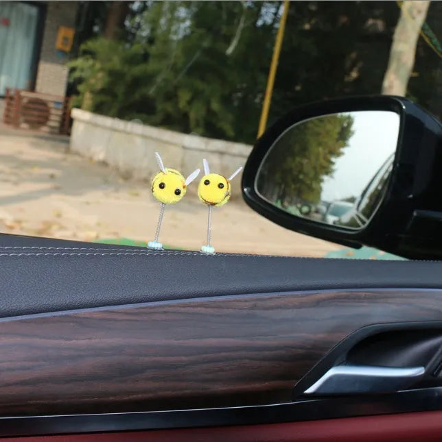Small, soft, cartoon bee car decoration made from yellow and black fur ball material.