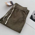 Man wearing beige loose straight-leg casual trousers with a drawstring waistband.