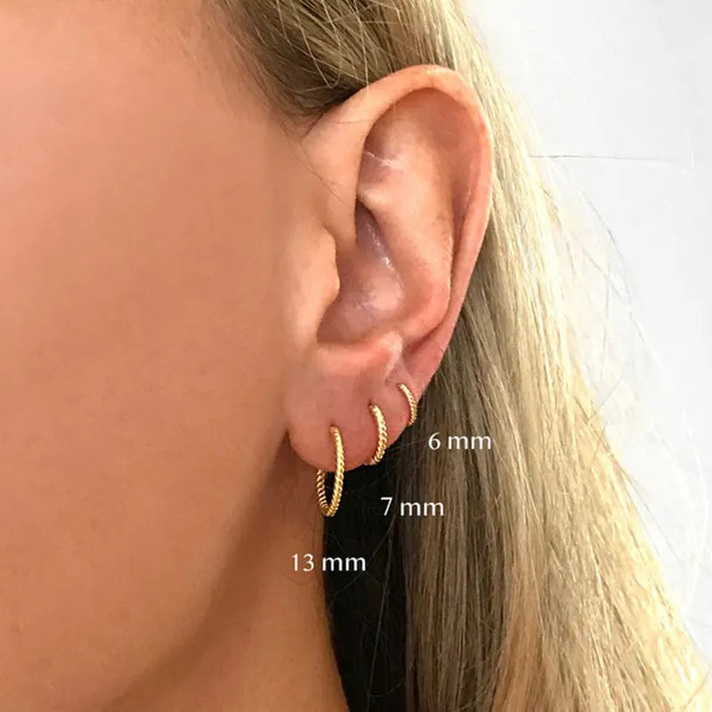 A pair of S925 sterling silver twisted string round hoop earrings on a gold background.