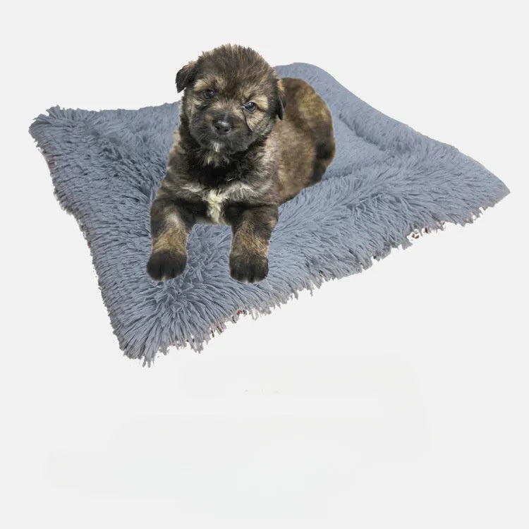 Grey plush pet blanket and bed with raised sides and a black non-slip bottom, shown on a wooden floor.