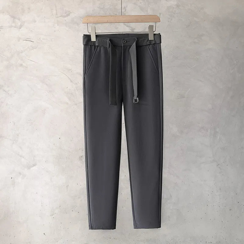Boy wearing slim straight wool trousers in a neutral colour, showing tapered leg and straight hem.