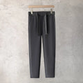 Boy wearing slim straight wool trousers in a neutral colour, showing tapered leg and straight hem.