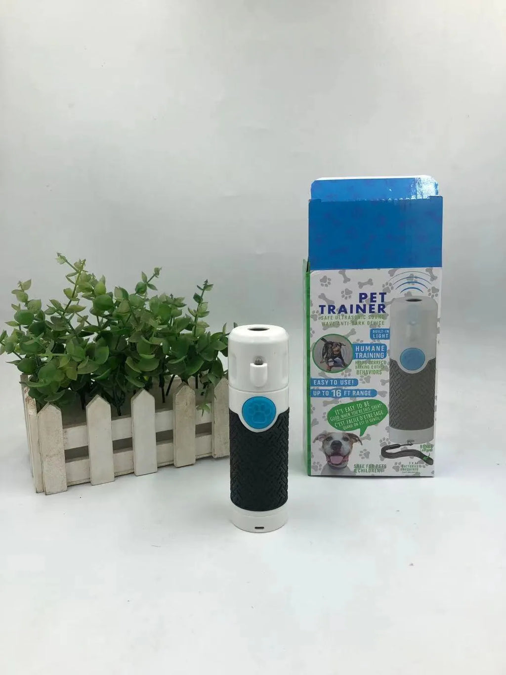 White handheld ultrasonic dog bark control trainer with AAA battery compartment.